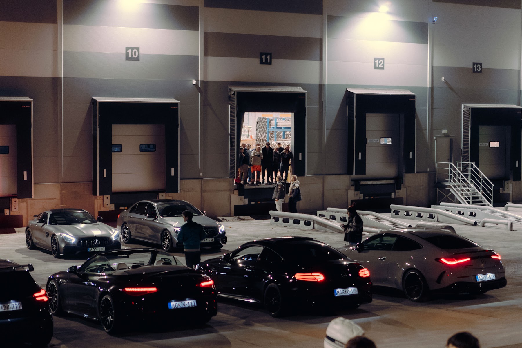Sportautók egy ipari épület előtt egy NightDrive estén